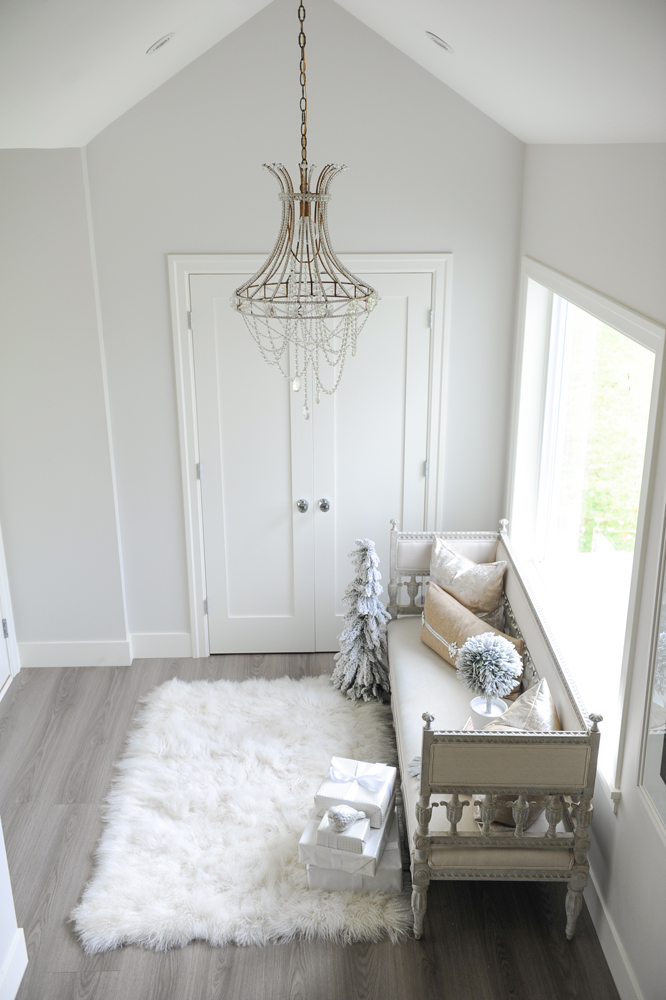 Modern white entrance with chandelier, furry rug and settee
