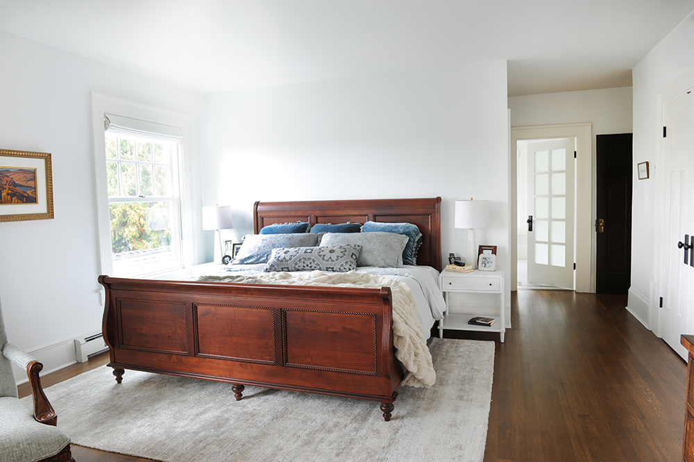 Master bedroom with a burnished wooden bed and silk area rug.