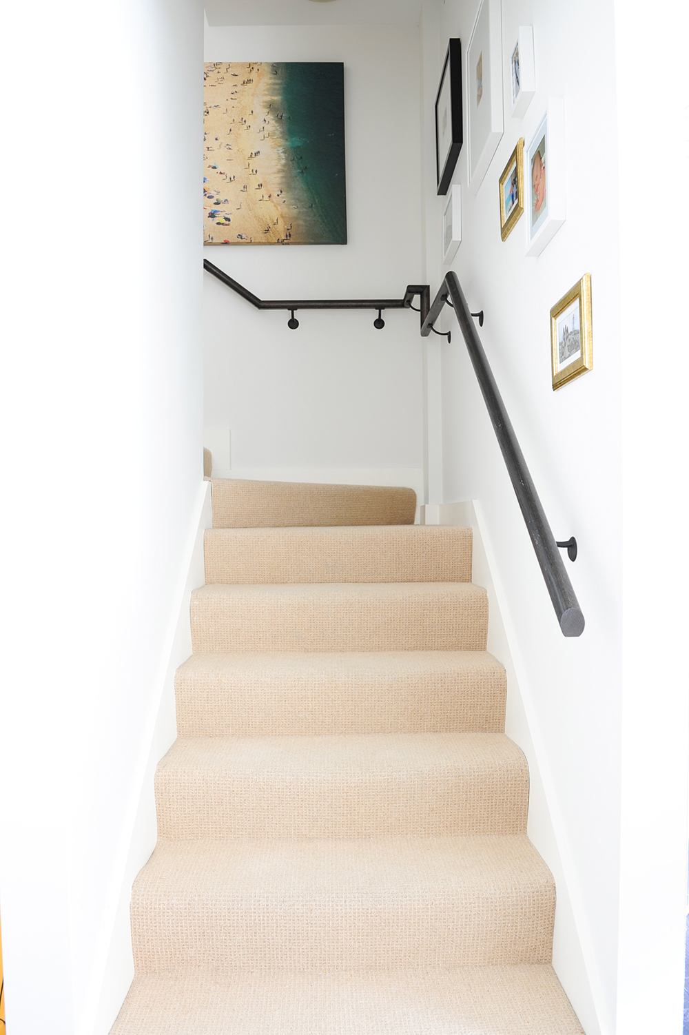 A carpeted staircase lined with artwork and photography.