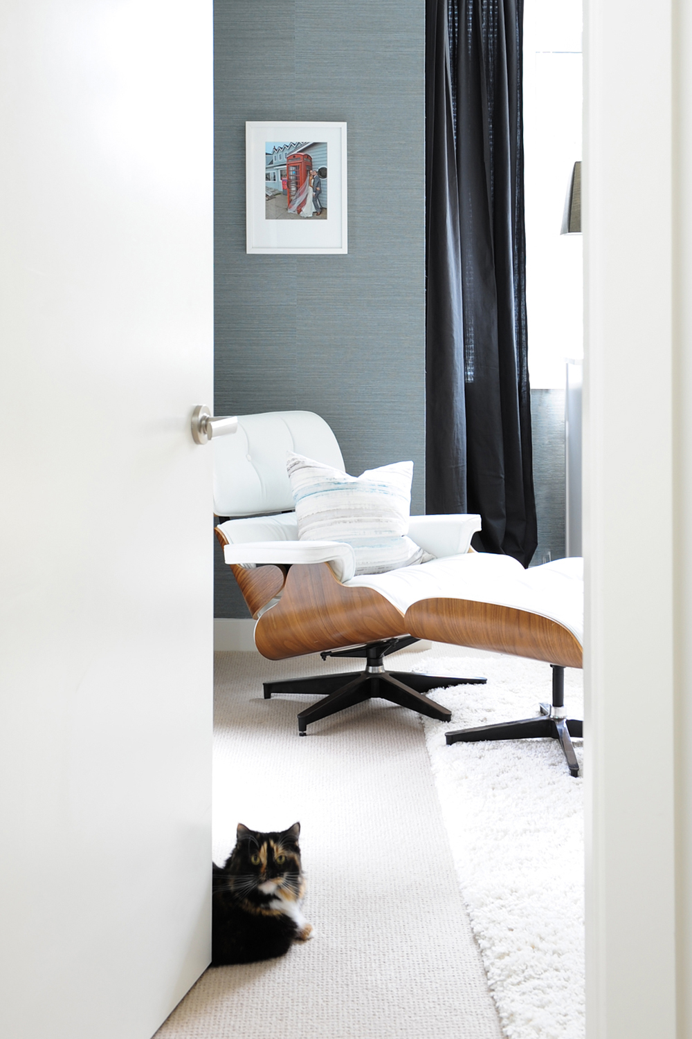 A master bedroom featuring a white leather Eames chair.