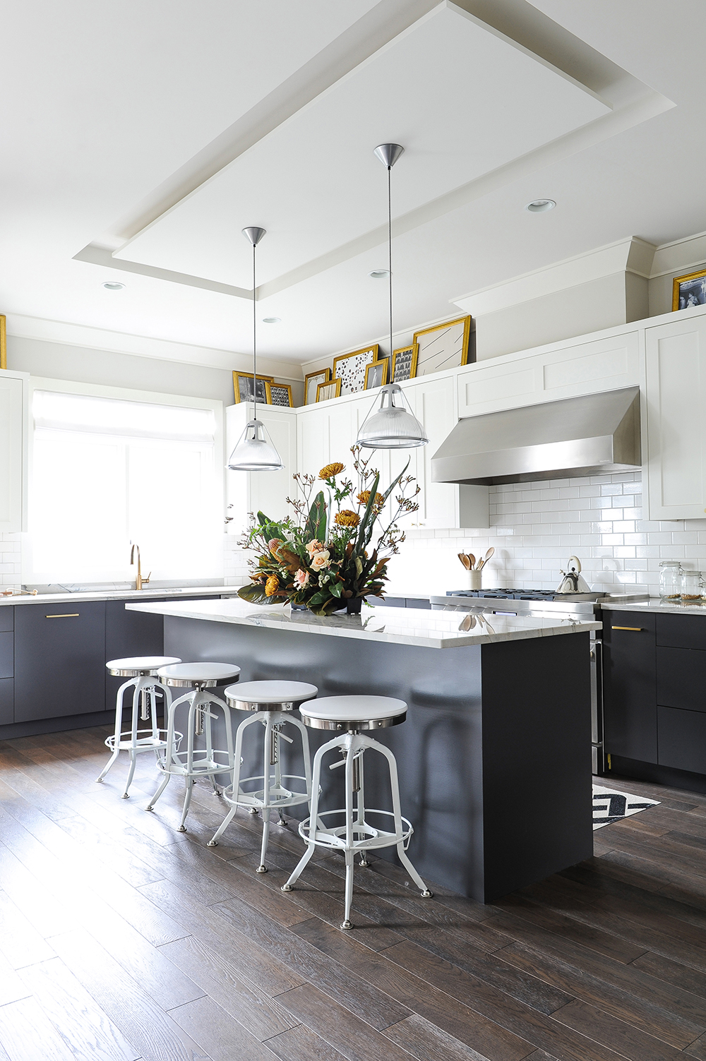 A bright white kitchen with grey cabinetry and gold accents.