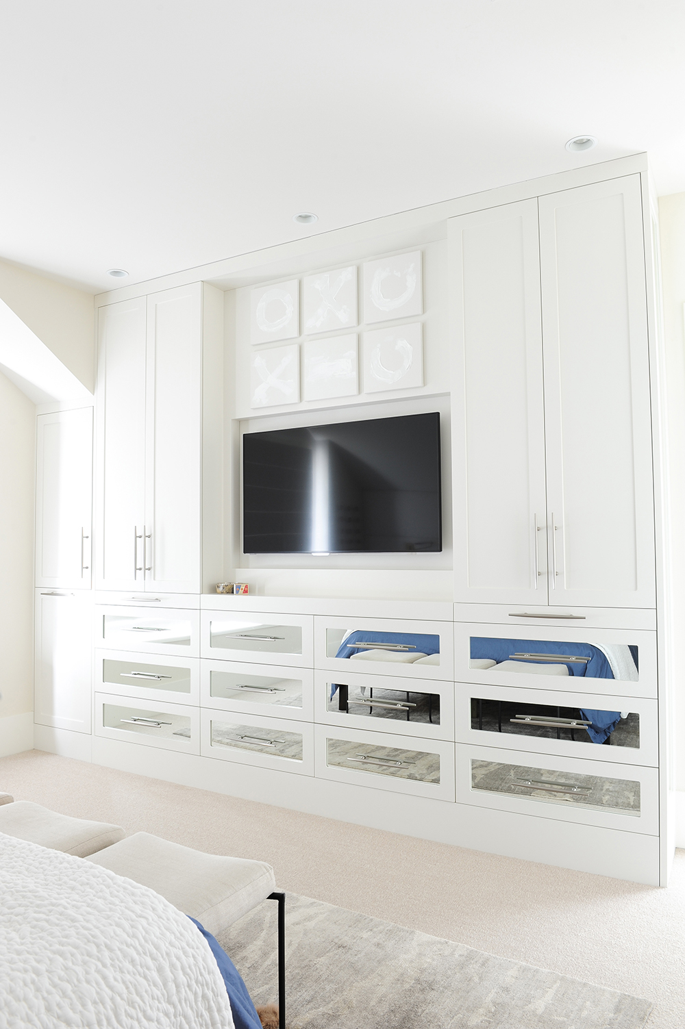 A large white built-in dresser with mirrored drawers visually expands the master bedroom.