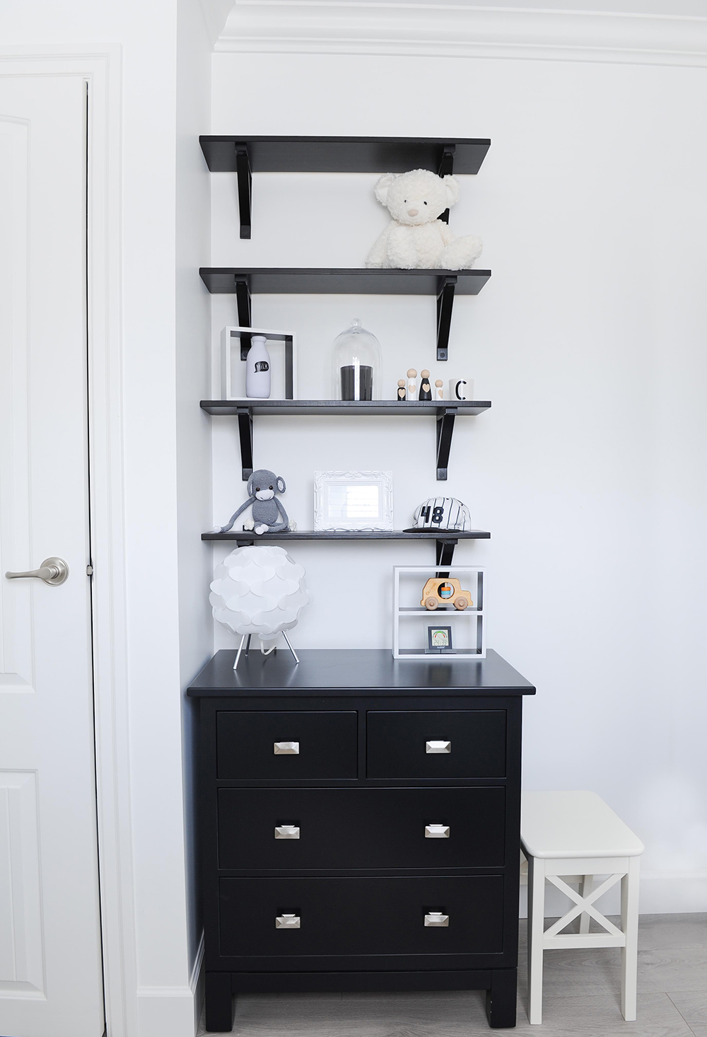 Sleek black wall-mounted shelves sit above a custom maple dresser.