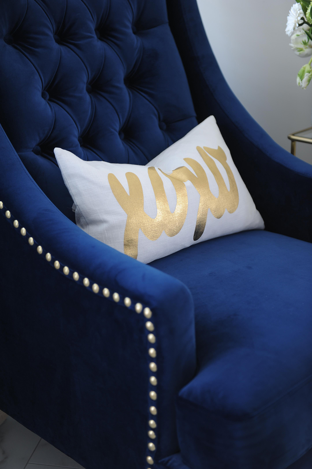 A stylish corner nook outfitted with a wing-backed royal blue and brass chair.