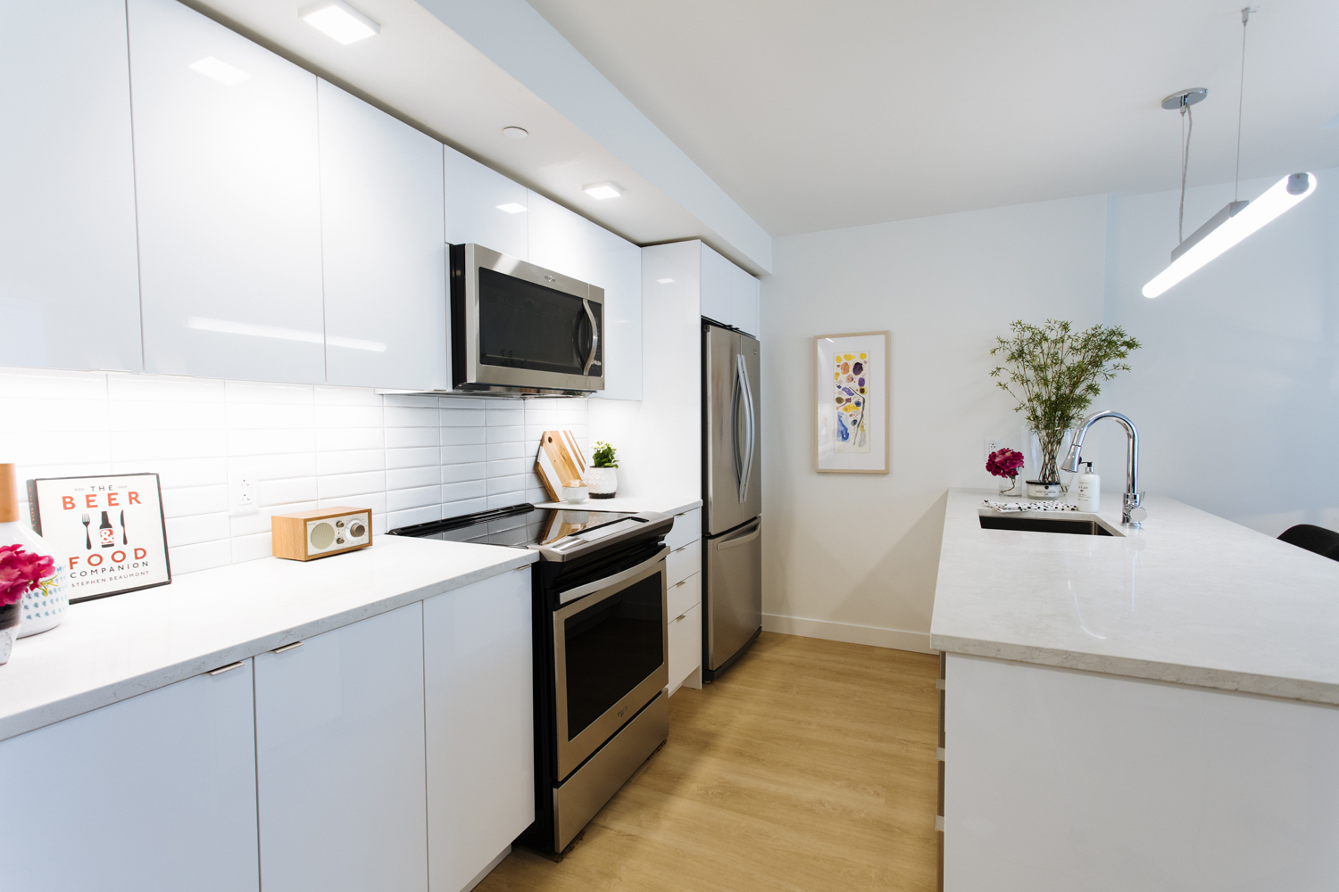 A white open-concept kitchen with all major appliances hidden from few and a few pops of colour on the walls and counter tops