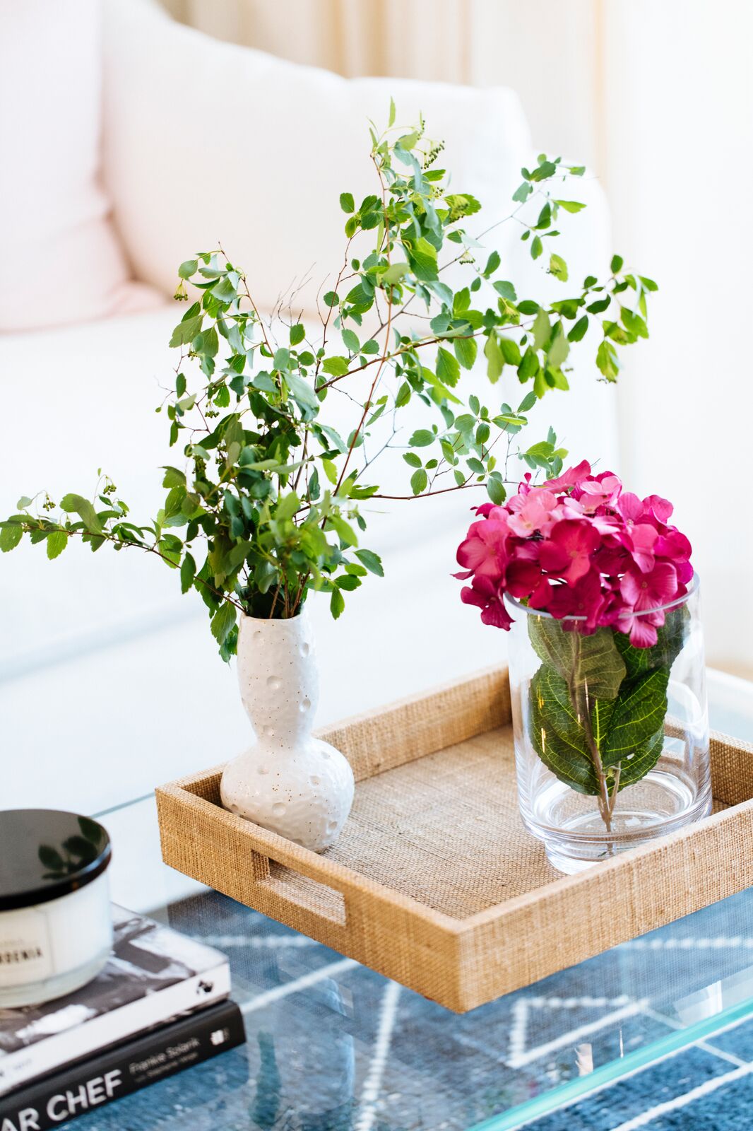 A tray with flower vases on a glass coffee table in the open-concept living room