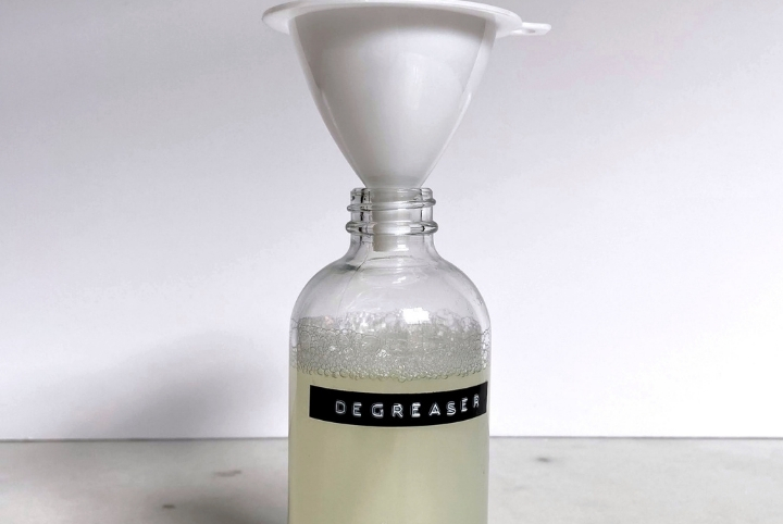 A bottle of homemade degreaser spray with a white funnel