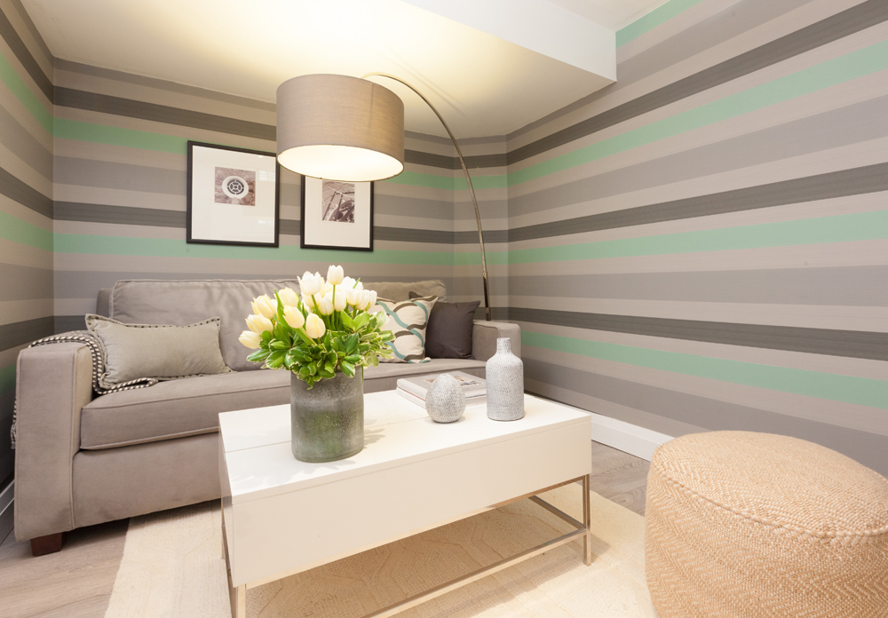 grey and green striped walls with grey sofa and white table