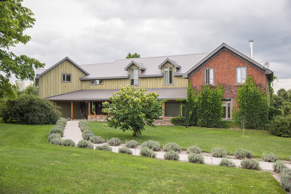 country house exterior with green wood siding and brick front section