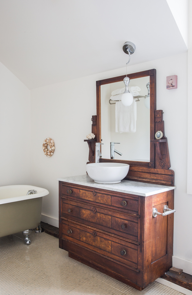 bathroom with old wood chest with marble top and vessel sink, green clawfoot tub