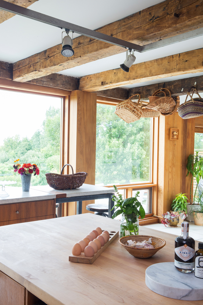 Kitchen with wood walls looking over wood top island and egg tray to windows and trees