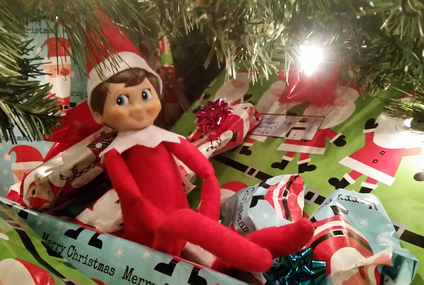 Elf on the shelf sitting under christmas tree