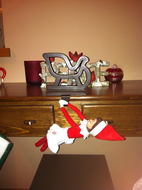 Elf on the Shelf hanging off a table