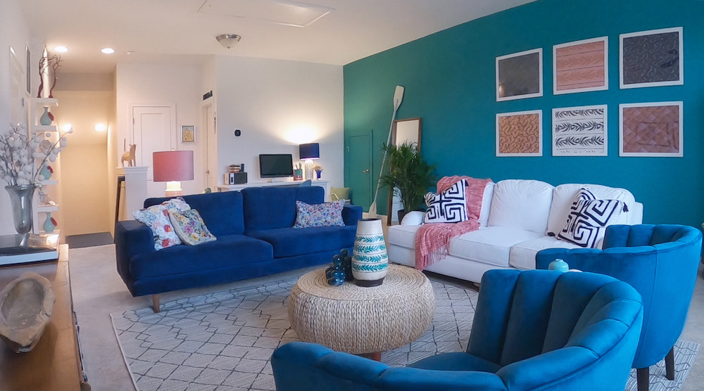 eclectic bonus room with blue wall, framed art and blue velvet couch