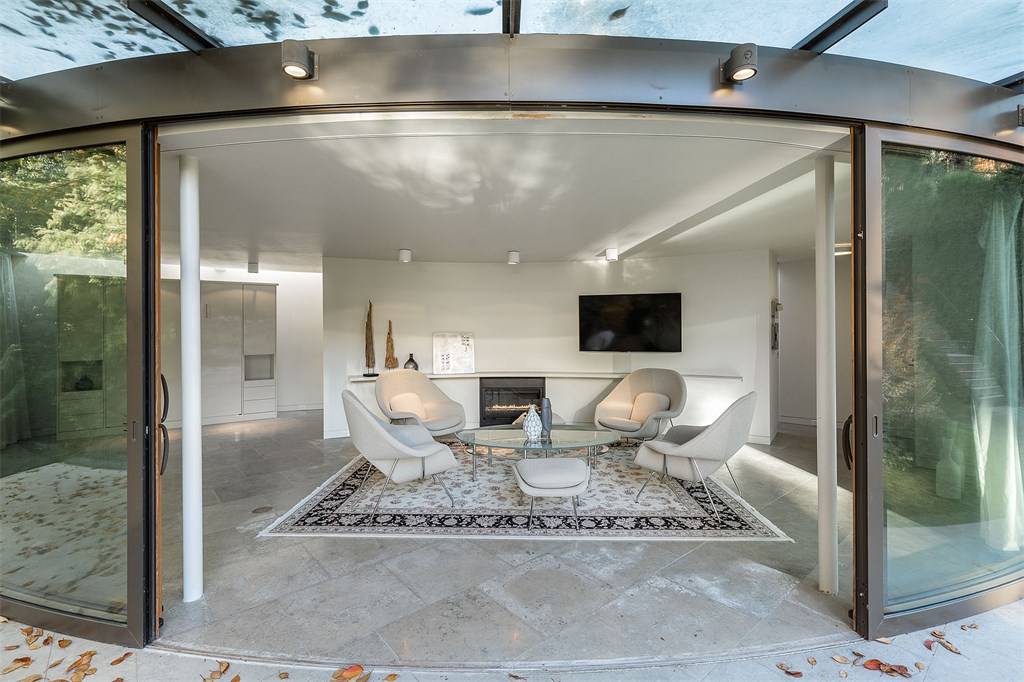 Stone tile flooring and curved sliding glass doors opening to an infinity pool in the family room