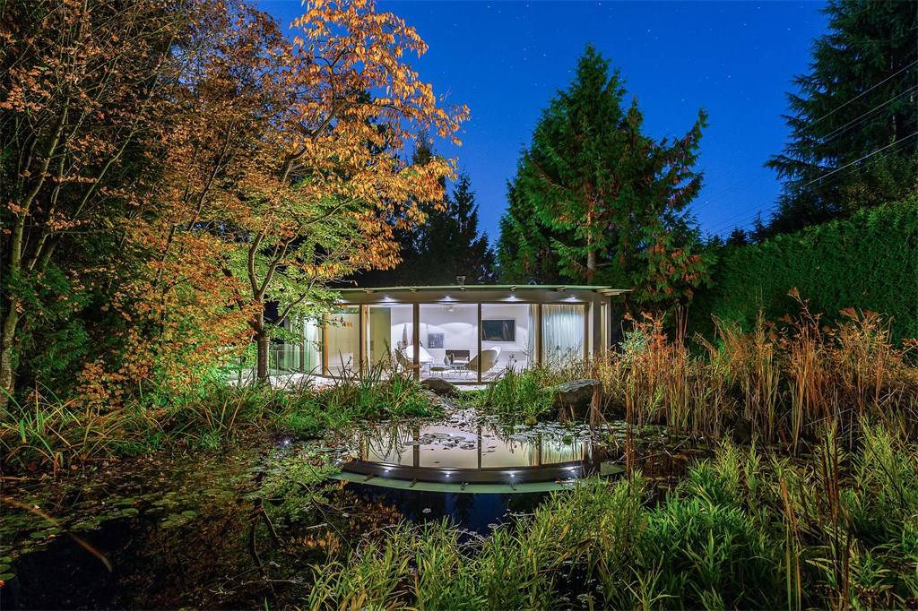 Glass carriage house behind West Vancouver mansion, surrounded by greenery