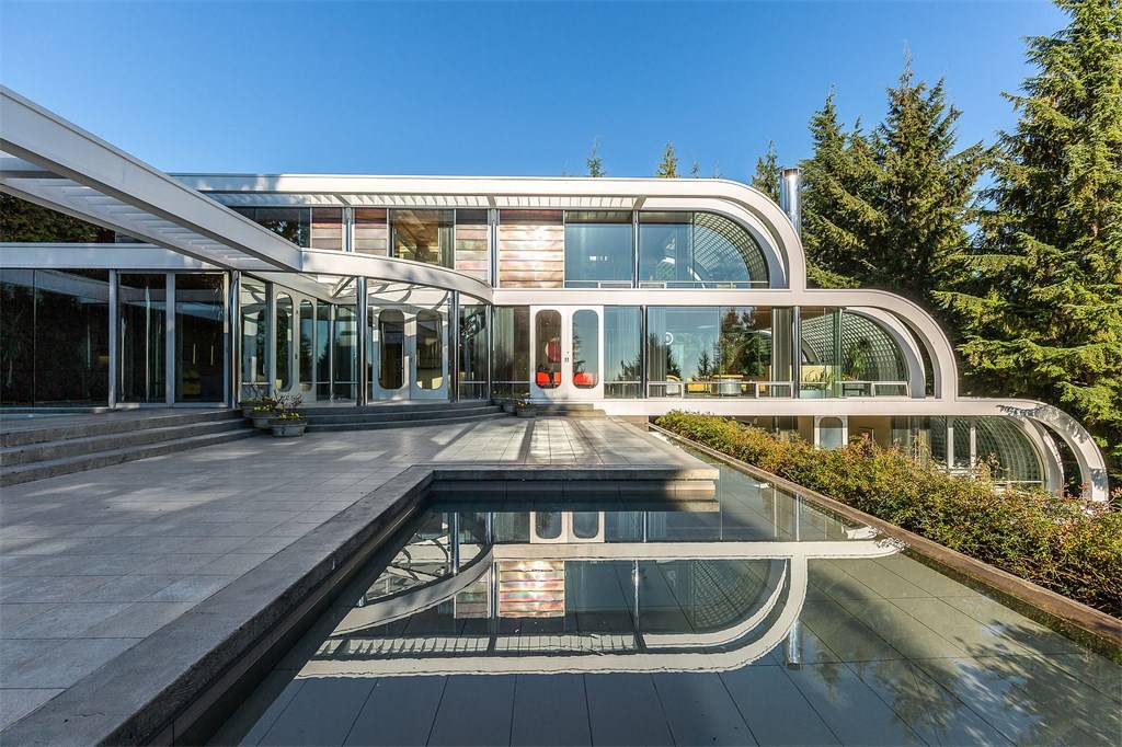 Backyard area of the glass and steel mansion overlooking forested area