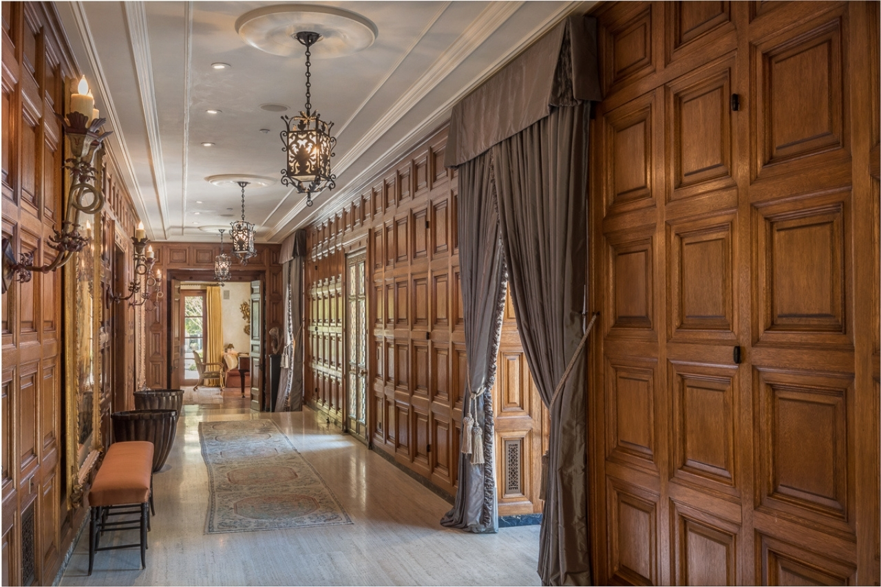 Walnut panels in a grand hallway with ornate light fixtures and art