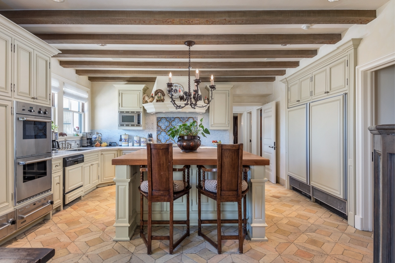 A chef's kitchen with luxe white cabinetry and exposed ceiling beams.