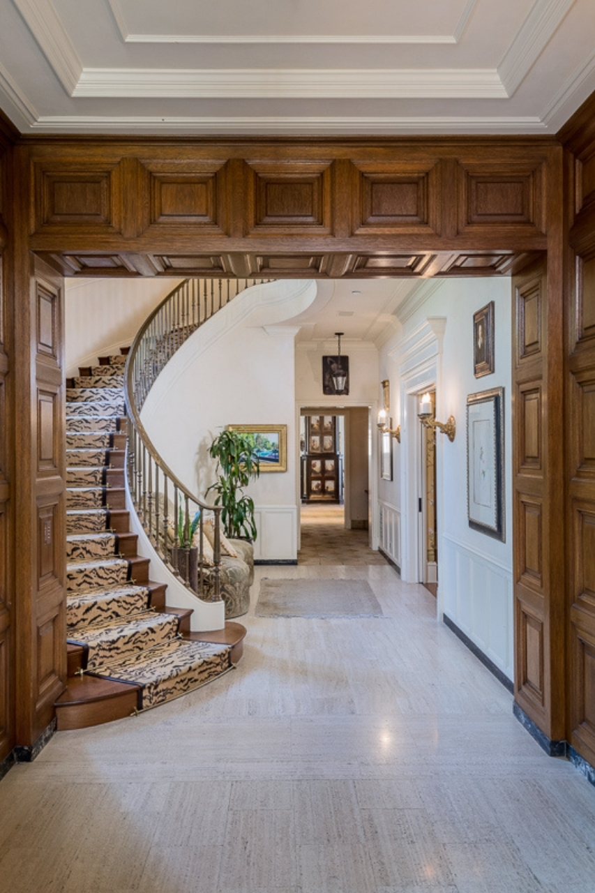 A traditional spiral staircase in a bright foyer with white walls.