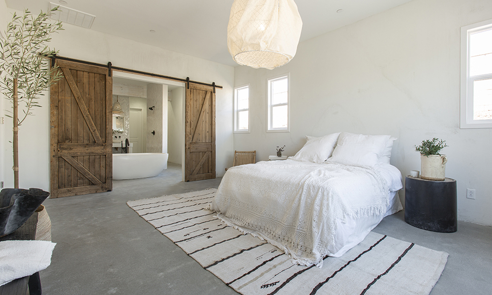 While bedroom with concrete floors leading to a bathroom.