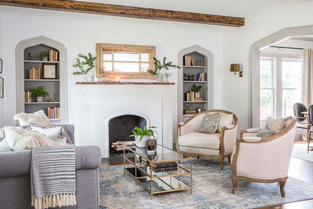 Joanna Gaines farmhouse living room with tub chairs, fringed blankets and a faded rug.