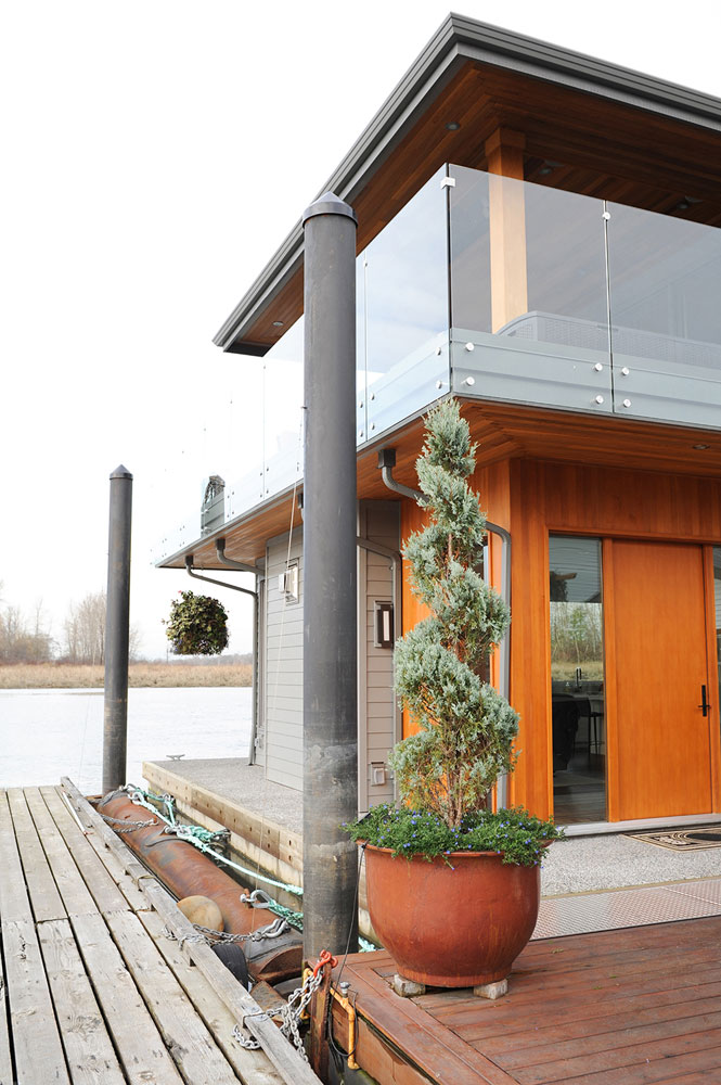 Exterior of cedar, glass and siding float home with plant by front door