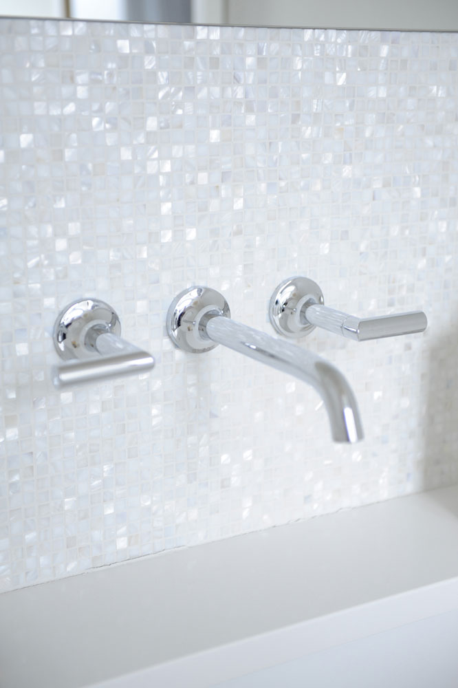 wall-mounted powder room faucet on shell mosaic backsplash