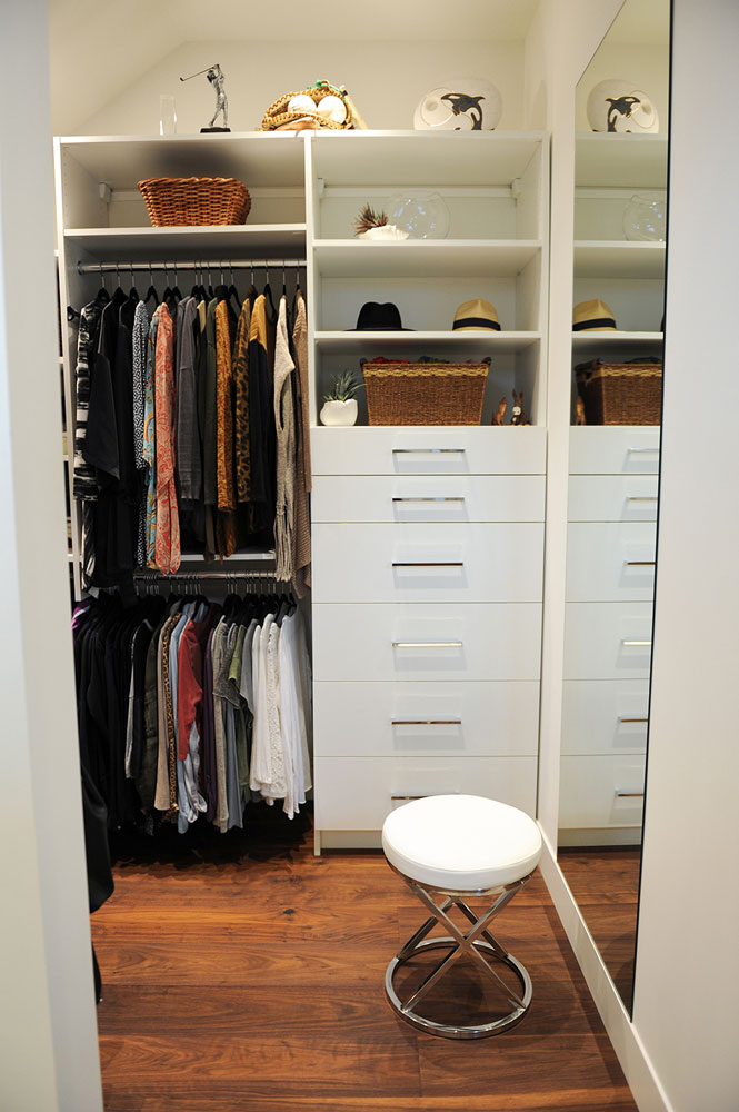 closet with white drawers, mirror and stool