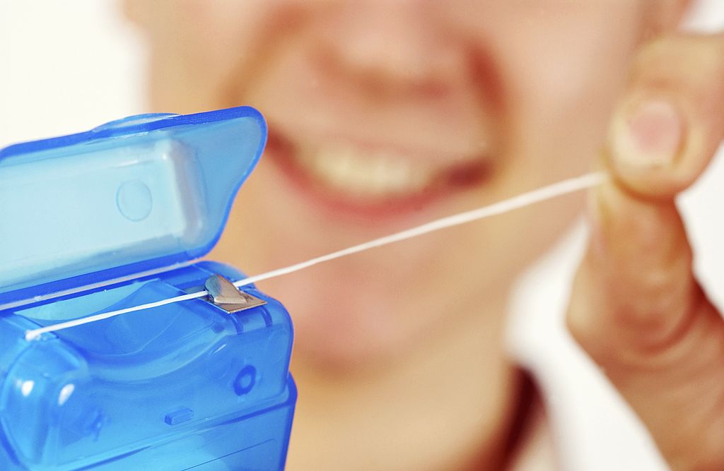 A smiling person extracting floss from the casing