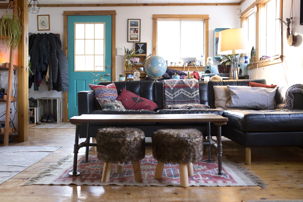 Living room with teal door, coffee table and furry stools