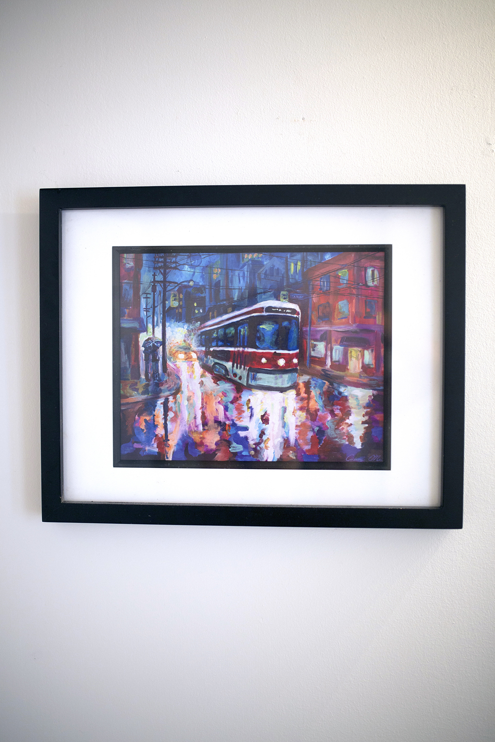 A painting of a TTC streetcar hanging in a minimalist bathroom