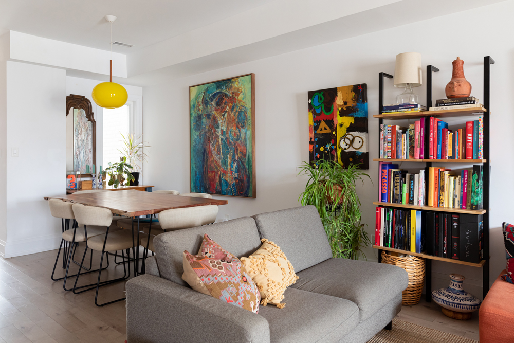 white open-concept living room and dining room with colourful paintings on the walls