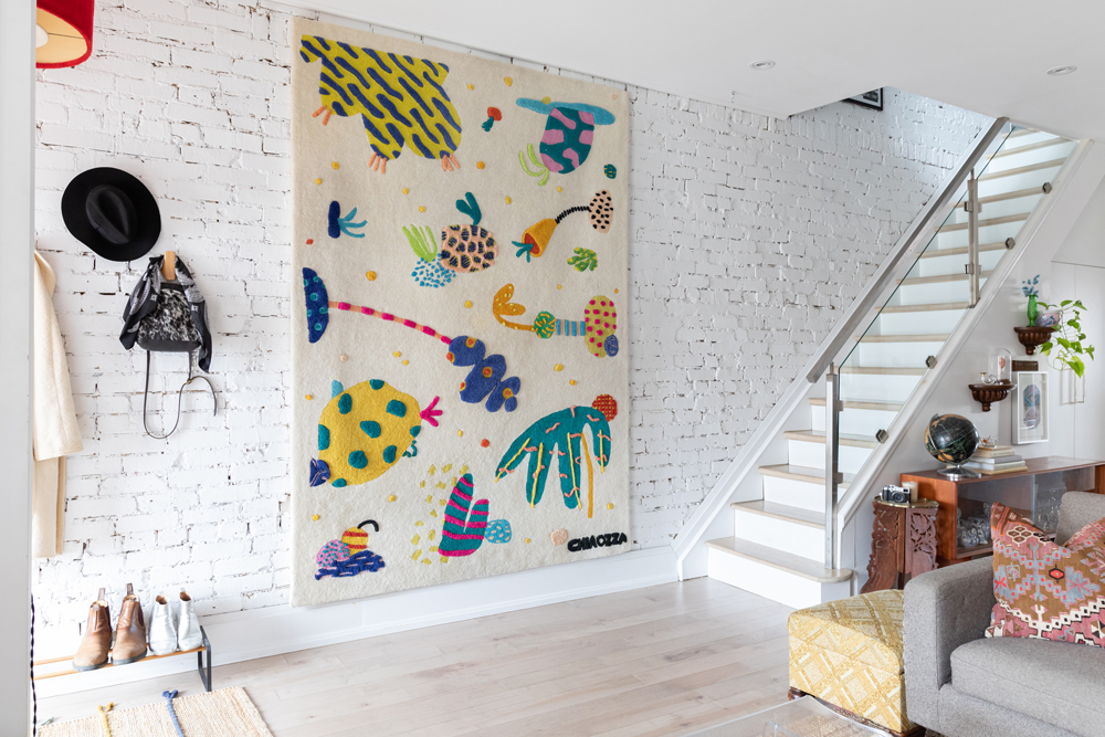 White brick wall with colourful wall tapestry and staircase