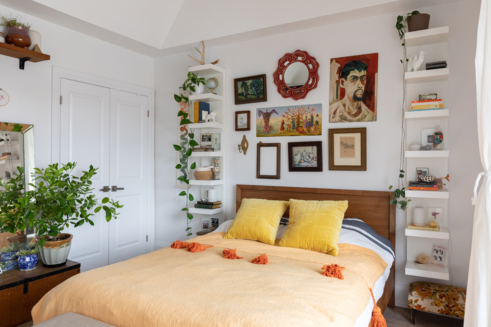 Yellow bed with gallery wall above and white floating shelves beside
