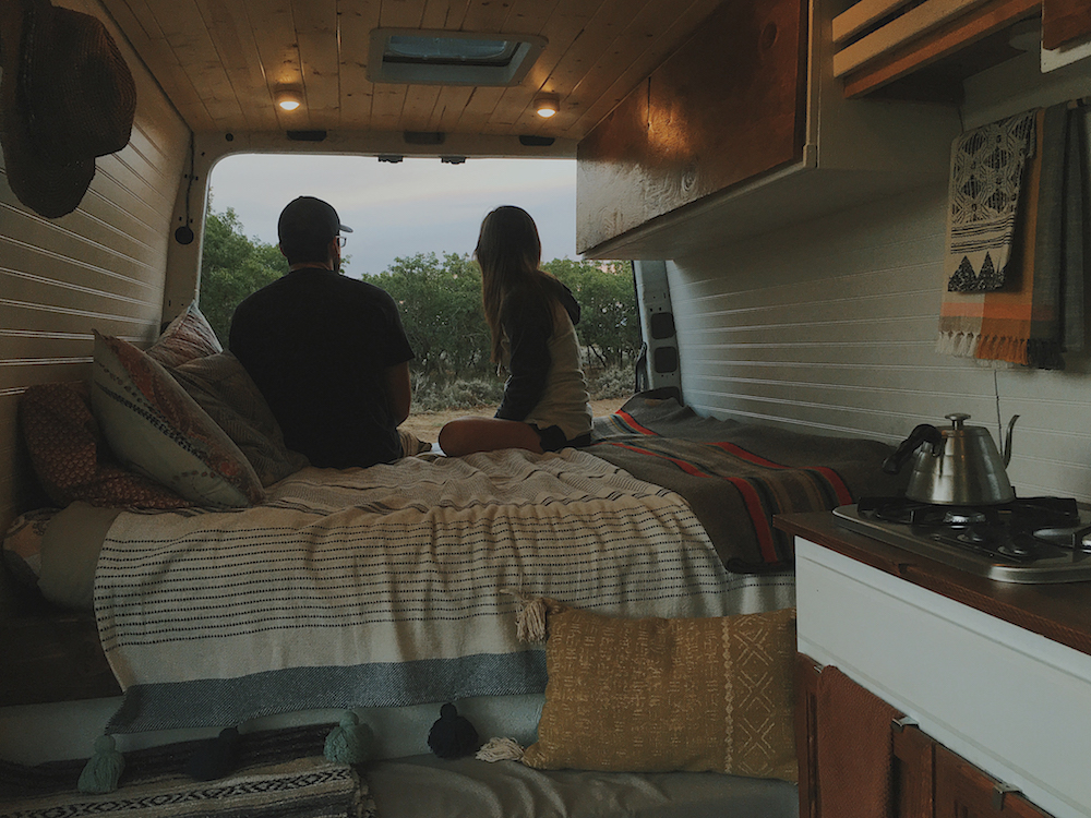 couple looks out of camper van with white walls