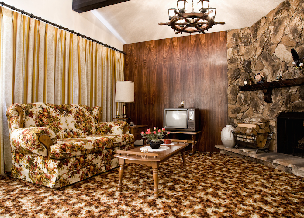 1970s-era living room with floral couch and wood-panel walls