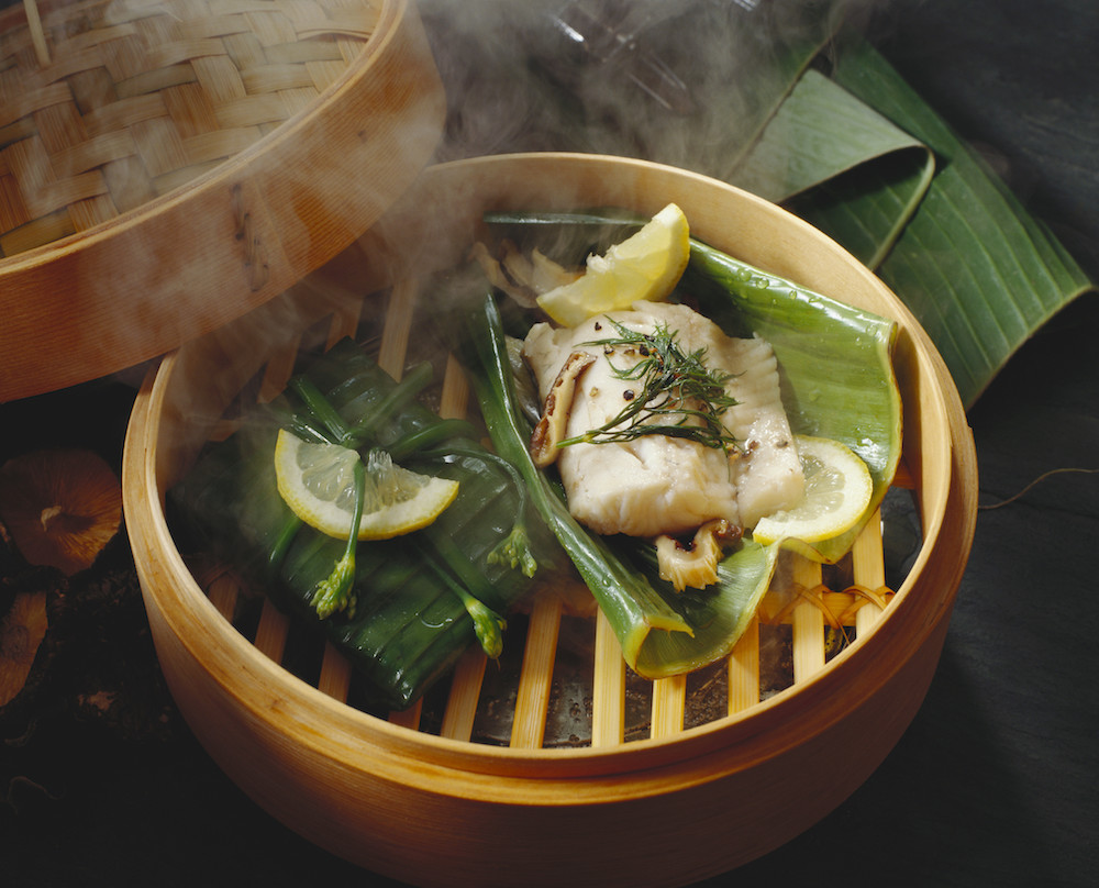 bamboo steamer with vegetables, lemon and fish inside