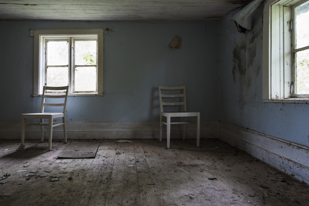 dirty blue room with two wooden chairs and window
