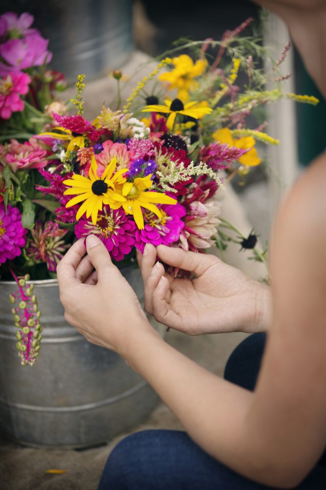 Cropped image of woman touching flowers in pot for sale at shop