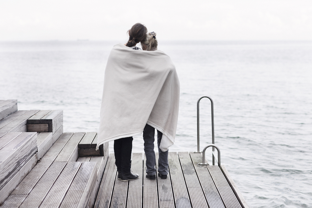 two women stand on dock with blanket