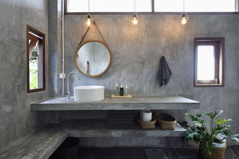 concrete-walled bathroom with round mirror and white basin sink