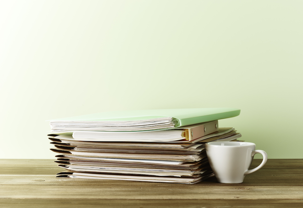 stack of files on wood desk in green room