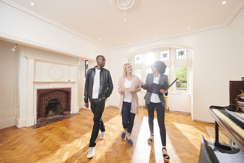 couple and real estate agent in empty living room