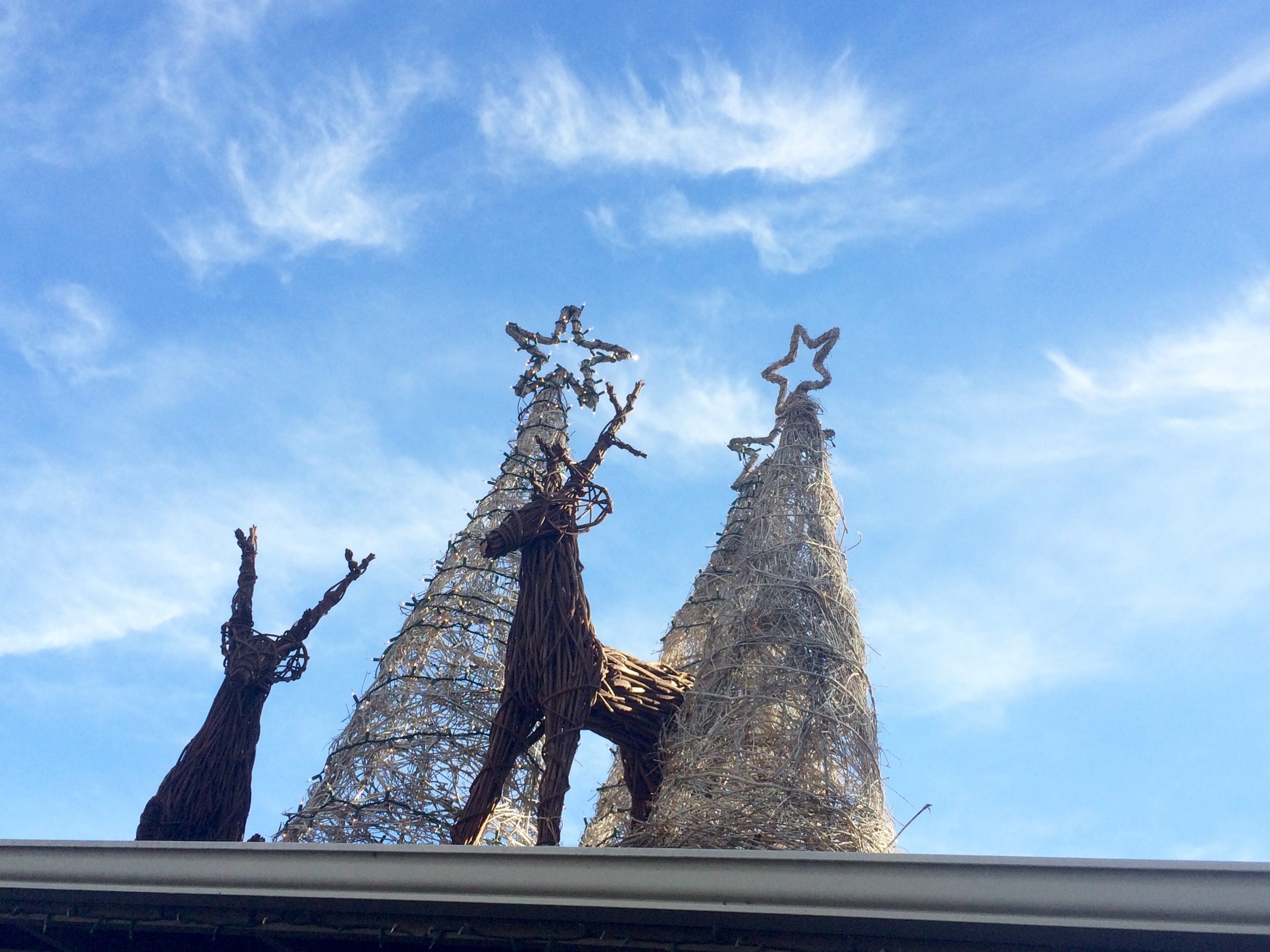 two reindeer decorations beside silver Christmas tree decorations on roof