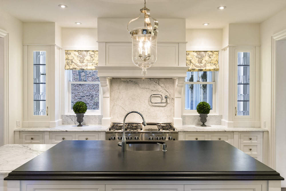 silver and glass pendent light hanging over kitchen island in modern white kitchen