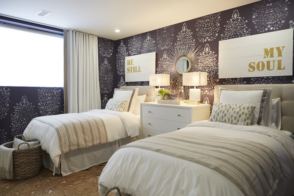 Twin beds in basement bedroom with wallpapered backdrop