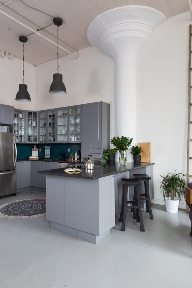 Black factory pendants lights, coordinating black stools and countertops against grey cabinetry