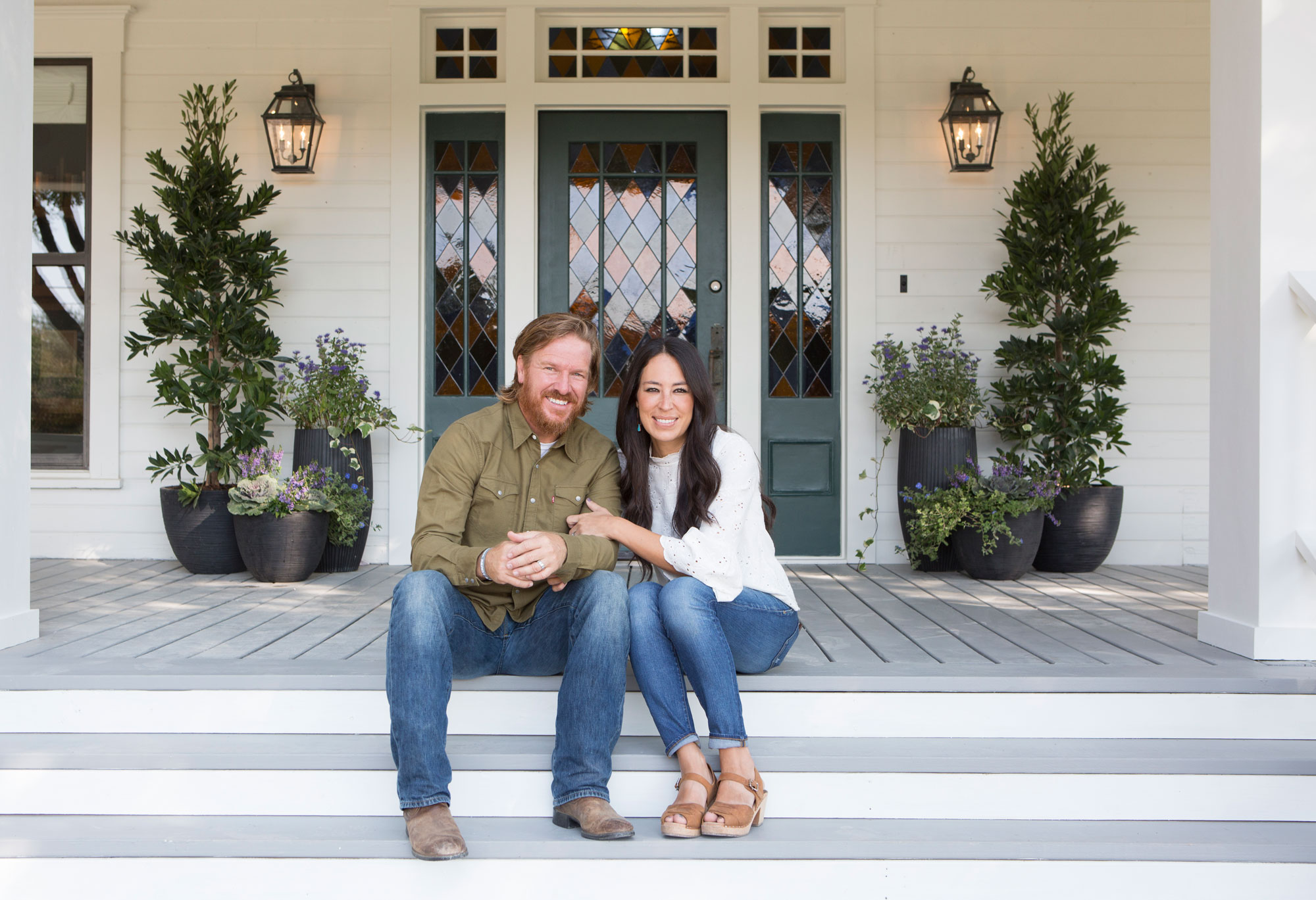 Chip and Joanna Gaines Sitting on a Front Porch.