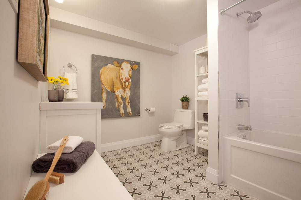 modern white bathroom with geometric-tile floor and a colourful cow painting on the wall